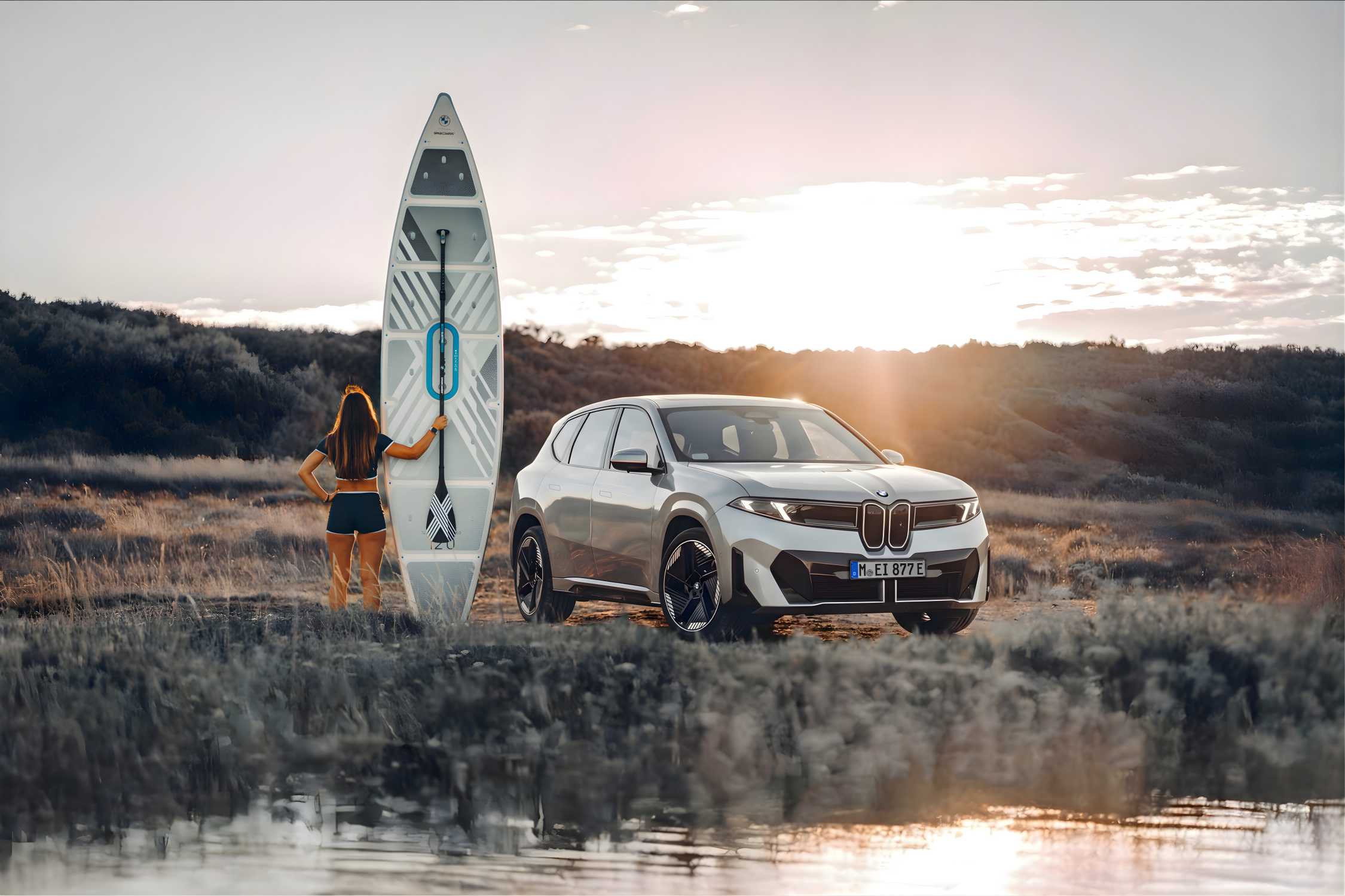 Official BMW image of a Neue Klasse iX3 beside a paddleboard on an electric road trip